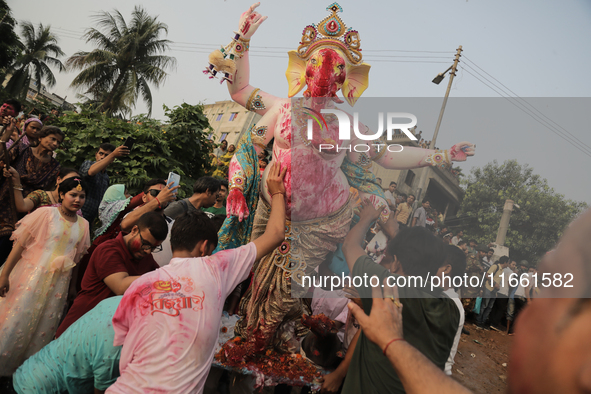 A Hindu devotee carries the idol of their goddess to be submerged in the river as part of their ritual in Dhaka, Bangladesh, on October 13,...