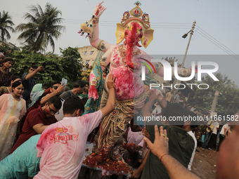 A Hindu devotee carries the idol of their goddess to be submerged in the river as part of their ritual in Dhaka, Bangladesh, on October 13,...