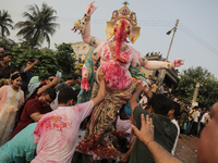 A Hindu devotee carries the idol of their goddess to be submerged in the river as part of their ritual in Dhaka, Bangladesh, on October 13,...