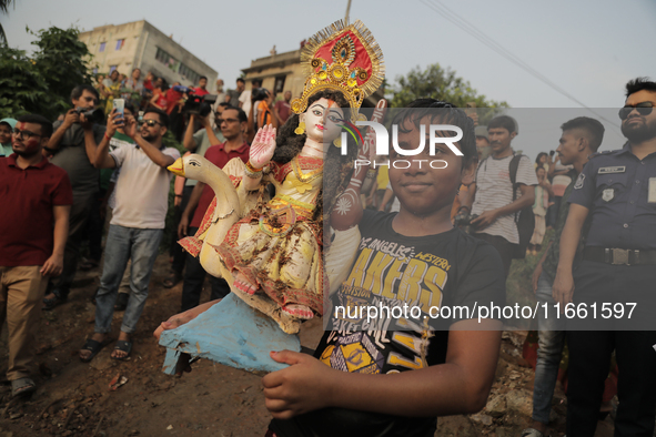 A Hindu devotee carries the idol of their goddess to be submerged in the river as part of their ritual in Dhaka, Bangladesh, on October 13,...