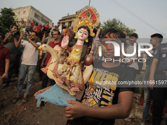 A Hindu devotee carries the idol of their goddess to be submerged in the river as part of their ritual in Dhaka, Bangladesh, on October 13,...