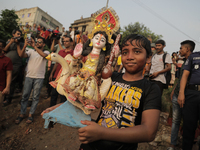 A Hindu devotee carries the idol of their goddess to be submerged in the river as part of their ritual in Dhaka, Bangladesh, on October 13,...