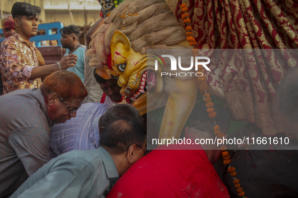 Hindu devotees immerse a clay idol of the Hindu Goddess Durga in the Buriganga River on the final day of the 'Durga Puja' festival in Dhaka,...