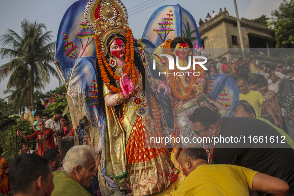 Hindu devotees immerse a clay idol of the Hindu Goddess Durga in the Buriganga River on the final day of the 'Durga Puja' festival in Dhaka,...