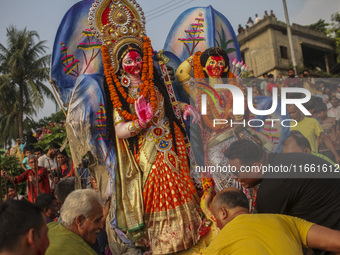 Hindu devotees immerse a clay idol of the Hindu Goddess Durga in the Buriganga River on the final day of the 'Durga Puja' festival in Dhaka,...