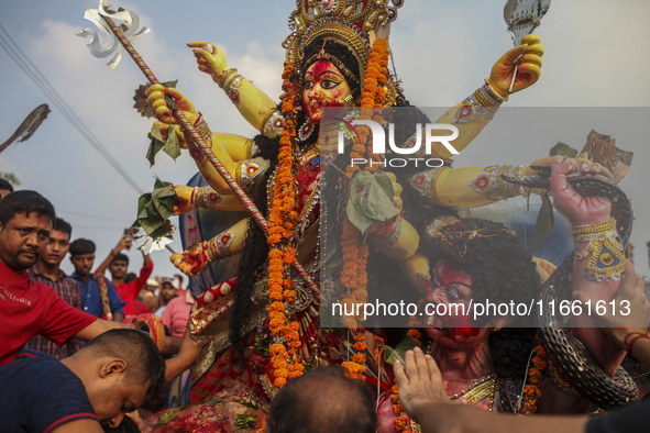 Hindu devotees immerse a clay idol of the Hindu Goddess Durga in the Buriganga River on the final day of the 'Durga Puja' festival in Dhaka,...