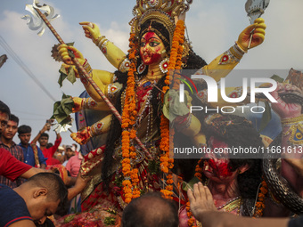 Hindu devotees immerse a clay idol of the Hindu Goddess Durga in the Buriganga River on the final day of the 'Durga Puja' festival in Dhaka,...