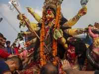 Hindu devotees immerse a clay idol of the Hindu Goddess Durga in the Buriganga River on the final day of the 'Durga Puja' festival in Dhaka,...