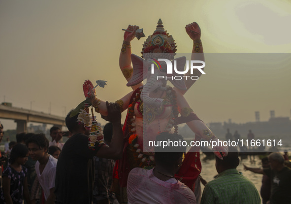 Hindu devotees immerse a clay idol of the Hindu Goddess Durga in the Buriganga River on the final day of the 'Durga Puja' festival in Dhaka,...