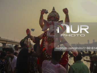 Hindu devotees immerse a clay idol of the Hindu Goddess Durga in the Buriganga River on the final day of the 'Durga Puja' festival in Dhaka,...