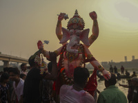 Hindu devotees immerse a clay idol of the Hindu Goddess Durga in the Buriganga River on the final day of the 'Durga Puja' festival in Dhaka,...