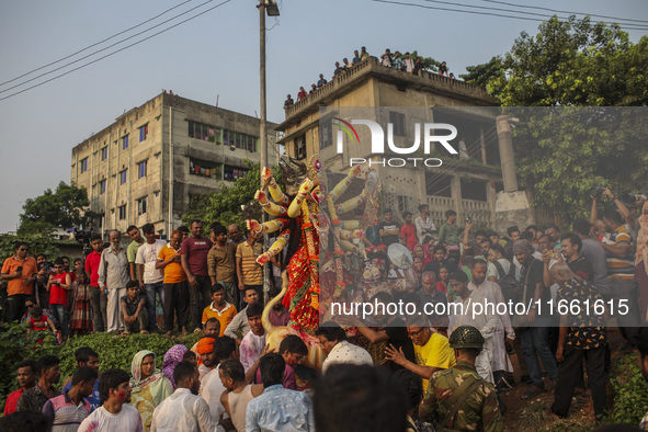 Hindu devotees immerse a clay idol of the Hindu Goddess Durga in the Buriganga River on the final day of the 'Durga Puja' festival in Dhaka,...