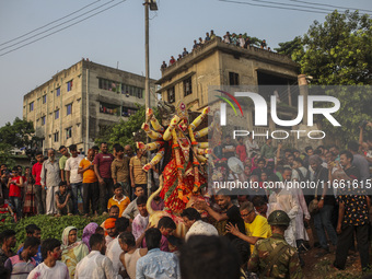 Hindu devotees immerse a clay idol of the Hindu Goddess Durga in the Buriganga River on the final day of the 'Durga Puja' festival in Dhaka,...