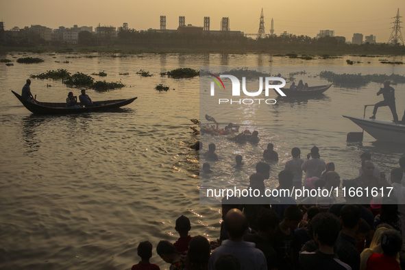 Hindu devotees immerse a clay idol of the Hindu Goddess Durga in the Buriganga River on the final day of the 'Durga Puja' festival in Dhaka,...