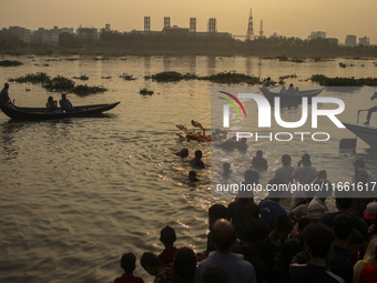 Hindu devotees immerse a clay idol of the Hindu Goddess Durga in the Buriganga River on the final day of the 'Durga Puja' festival in Dhaka,...