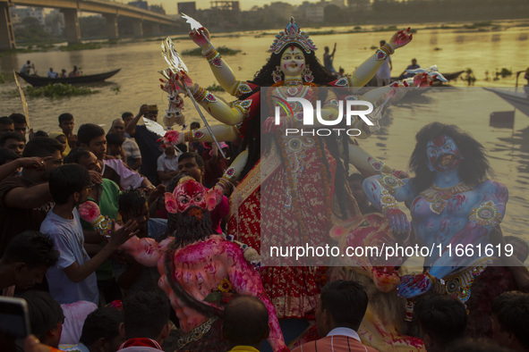 Hindu devotees immerse a clay idol of the Hindu Goddess Durga in the Buriganga River on the final day of the 'Durga Puja' festival in Dhaka,...