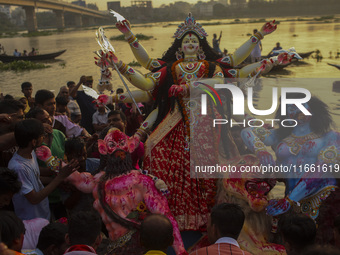 Hindu devotees immerse a clay idol of the Hindu Goddess Durga in the Buriganga River on the final day of the 'Durga Puja' festival in Dhaka,...