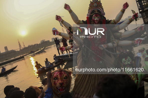 Hindu devotees immerse a clay idol of the Hindu Goddess Durga in the Buriganga River on the final day of the 'Durga Puja' festival in Dhaka,...