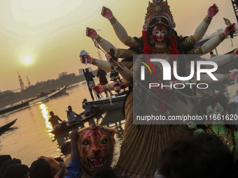 Hindu devotees immerse a clay idol of the Hindu Goddess Durga in the Buriganga River on the final day of the 'Durga Puja' festival in Dhaka,...