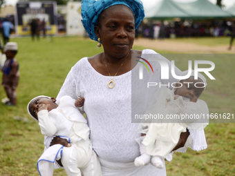 A woman carries twins during the 2024 edition of the annual World Twins Festival in Igbo-Ora, the Land of Twins, in Oyo State, Nigeria, on O...