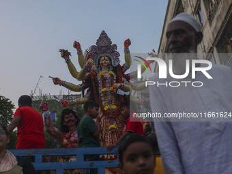 Hindu devotees immerse a clay idol of the Hindu Goddess Durga in the Buriganga River on the final day of the 'Durga Puja' festival in Dhaka,...