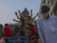 Hindu devotees immerse a clay idol of the Hindu Goddess Durga in the Buriganga River on the final day of the 'Durga Puja' festival in Dhaka,...