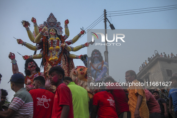 Hindu devotees immerse a clay idol of the Hindu Goddess Durga in the Buriganga River on the final day of the 'Durga Puja' festival in Dhaka,...