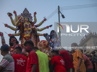 Hindu devotees immerse a clay idol of the Hindu Goddess Durga in the Buriganga River on the final day of the 'Durga Puja' festival in Dhaka,...