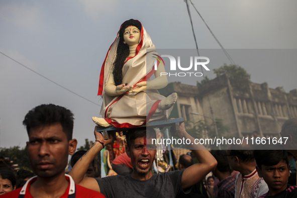 Hindu devotees immerse a clay idol of the Hindu Goddess Durga in the Buriganga River on the final day of the 'Durga Puja' festival in Dhaka,...