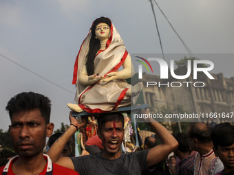 Hindu devotees immerse a clay idol of the Hindu Goddess Durga in the Buriganga River on the final day of the 'Durga Puja' festival in Dhaka,...