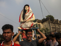 Hindu devotees immerse a clay idol of the Hindu Goddess Durga in the Buriganga River on the final day of the 'Durga Puja' festival in Dhaka,...