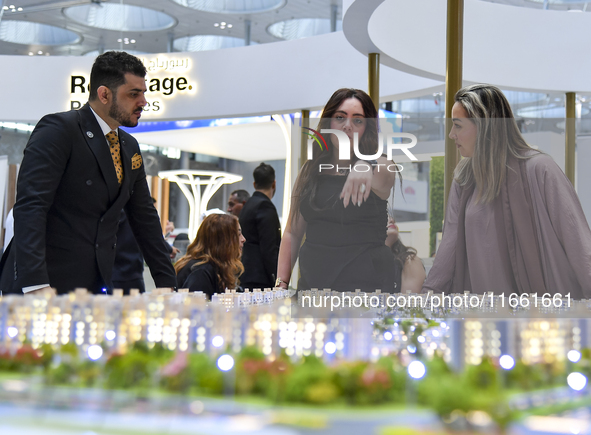 A saleswoman introduces a property to a potential buyer at the Cityscape Qatar 2024 real estate exhibition at the Doha Exhibition and Conven...