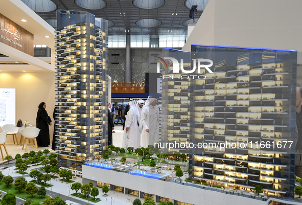 Visitors view models of a new building at the 'Cityscape Qatar 2024' real estate exhibition at the Doha Exhibition and Convention Center in...