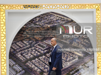 A visitor walks past a billboard showing the Al Waab City project at the Cityscape Qatar 2024 real estate exhibition at the Doha Exhibition...