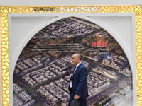 A visitor walks past a billboard showing the Al Waab City project at the Cityscape Qatar 2024 real estate exhibition at the Doha Exhibition...