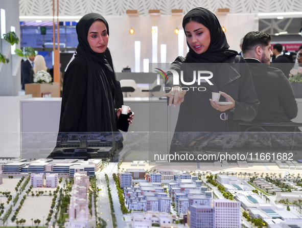 A saleswoman introduces property to a potential buyer at the Cityscape Qatar 2024 real estate exhibition at the Doha Exhibition and Conventi...