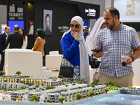 Visitors view models of a new building at the 'Cityscape Qatar 2024' real estate exhibition at the Doha Exhibition and Convention Center in...