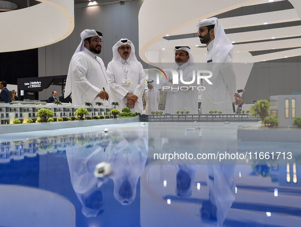 Visitors view models of a new building at the 'Cityscape Qatar 2024' real estate exhibition at the Doha Exhibition and Convention Center in...