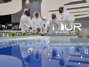 Visitors view models of a new building at the 'Cityscape Qatar 2024' real estate exhibition at the Doha Exhibition and Convention Center in...