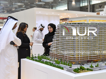 Visitors view models of a new building at the 'Cityscape Qatar 2024' real estate exhibition at the Doha Exhibition and Convention Center in...