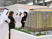 Visitors view models of a new building at the 'Cityscape Qatar 2024' real estate exhibition at the Doha Exhibition and Convention Center in...