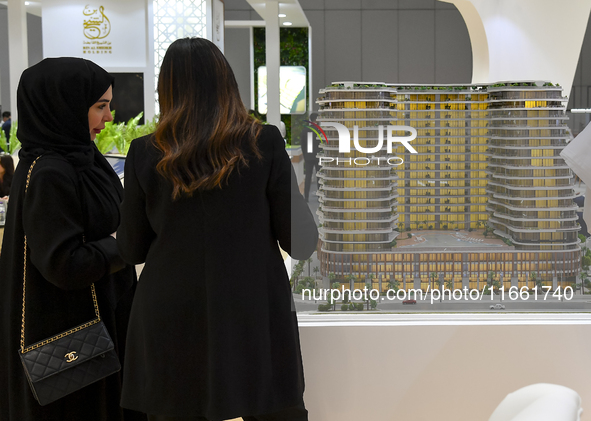 Visitors view models of a new building at the 'Cityscape Qatar 2024' real estate exhibition at the Doha Exhibition and Convention Center in...