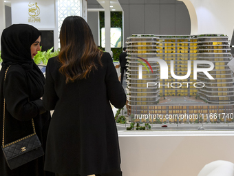 Visitors view models of a new building at the 'Cityscape Qatar 2024' real estate exhibition at the Doha Exhibition and Convention Center in...