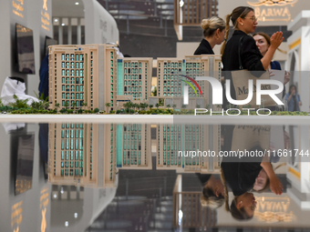 Visitors view models of a new building at the 'Cityscape Qatar 2024' real estate exhibition at the Doha Exhibition and Convention Center in...