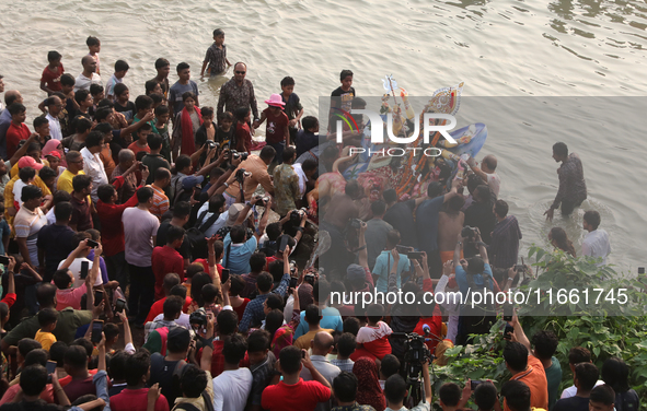 Bangladeshi Hindu devotees carry an idol of the Hindu Goddess Durga to immerse in the Buriganga River during the final day of the Durga Puja...