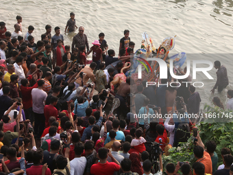 Bangladeshi Hindu devotees carry an idol of the Hindu Goddess Durga to immerse in the Buriganga River during the final day of the Durga Puja...