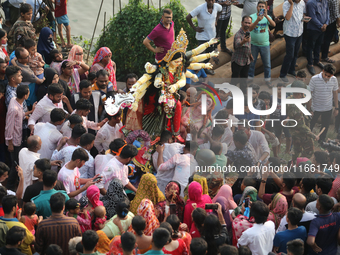 Bangladeshi Hindu devotees carry an idol of the Hindu Goddess Durga to immerse in the Buriganga River during the final day of the Durga Puja...