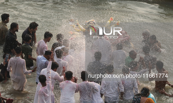 Bangladeshi Hindu devotees carry an idol of the Hindu Goddess Durga to immerse in the Buriganga River during the final day of the Durga Puja...