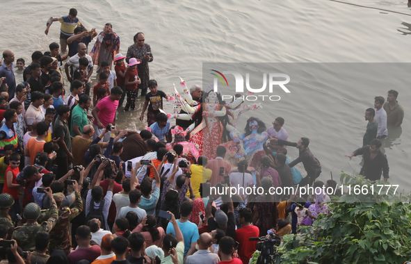 Bangladeshi Hindu devotees carry an idol of the Hindu Goddess Durga to immerse in the Buriganga River during the final day of the Durga Puja...