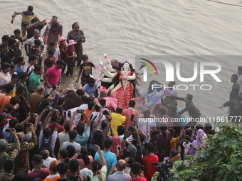 Bangladeshi Hindu devotees carry an idol of the Hindu Goddess Durga to immerse in the Buriganga River during the final day of the Durga Puja...